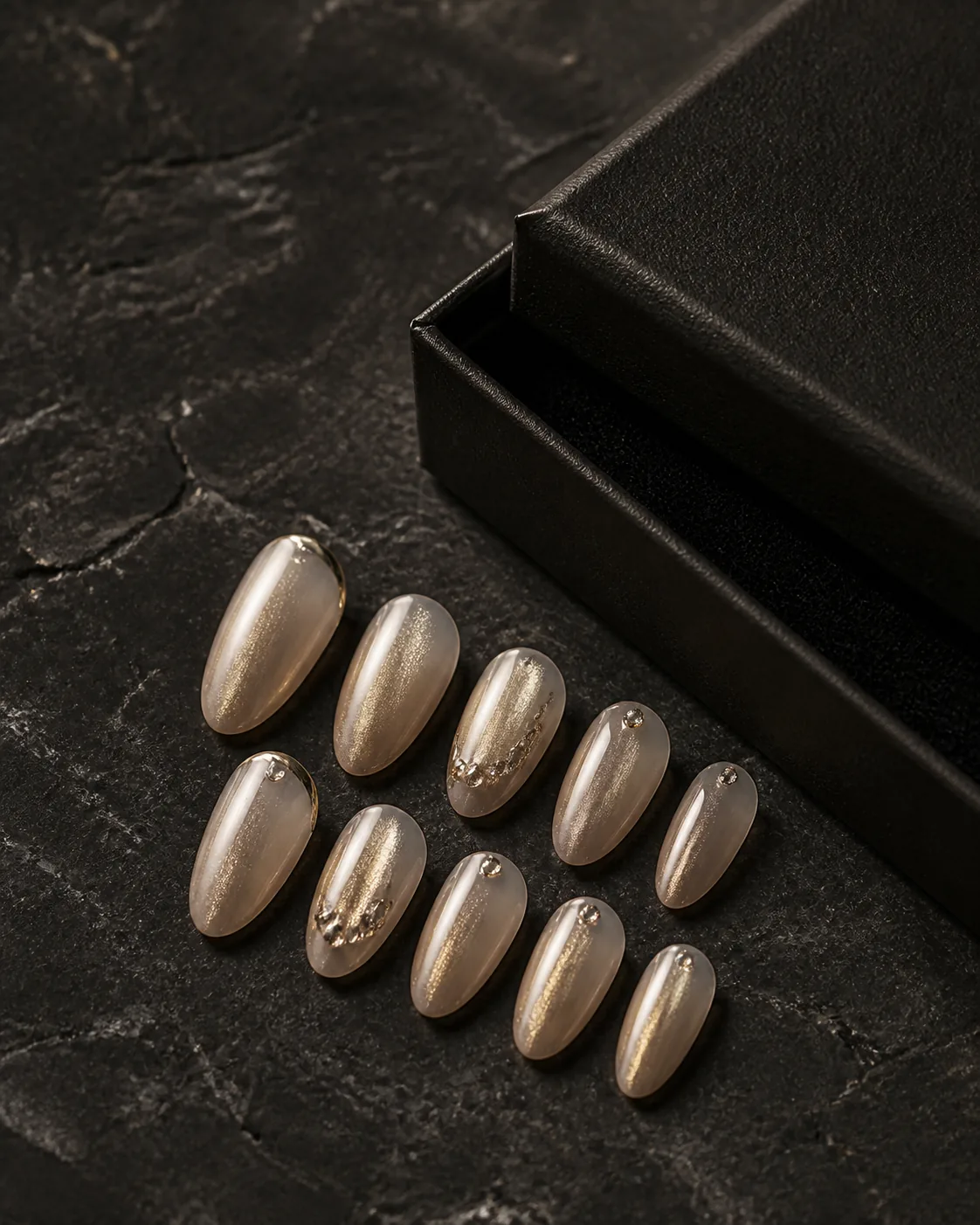 Champagne crystal glaze handcrafted press-on nails beside a black jewellery box